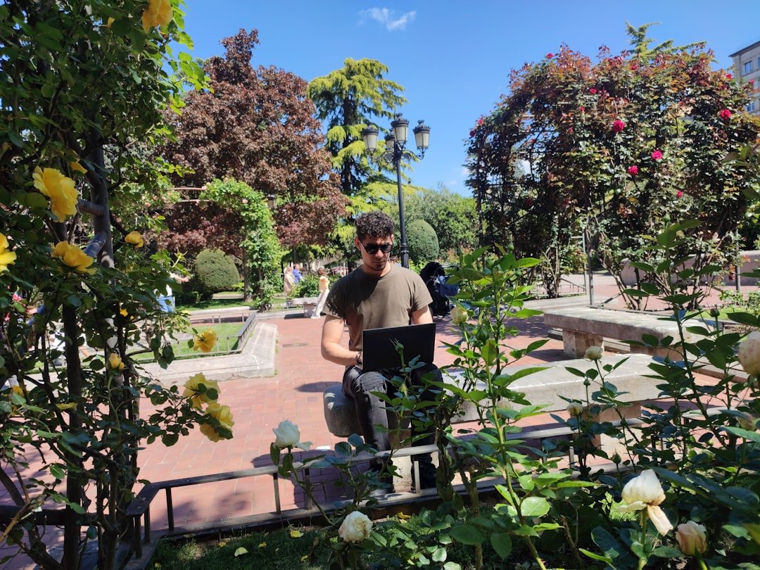 Urban forager examining plants near a California city park pathway, checking for signs of pesticide use